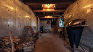 Un interior rústico con una escalera de madera, una chimenea y un cántaro de metal.