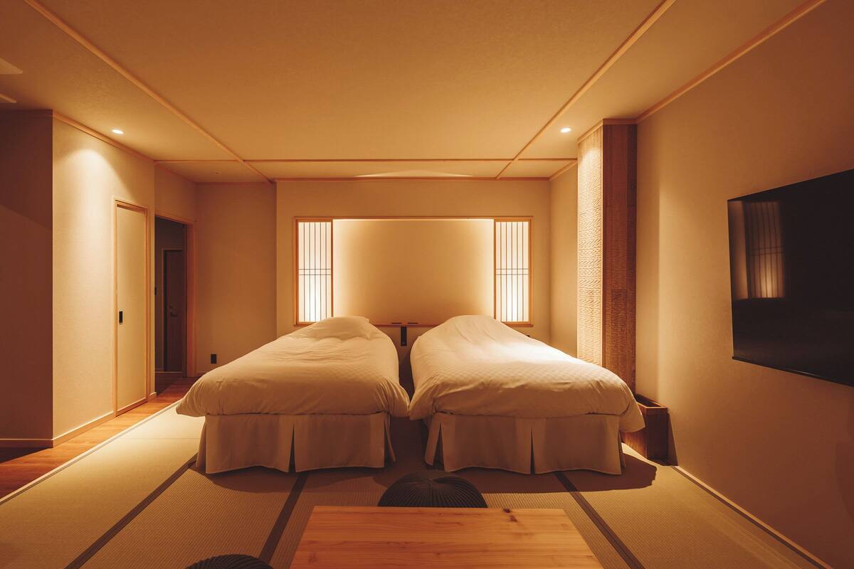 Una habitación con dos camas, televisión y puertas correderas.