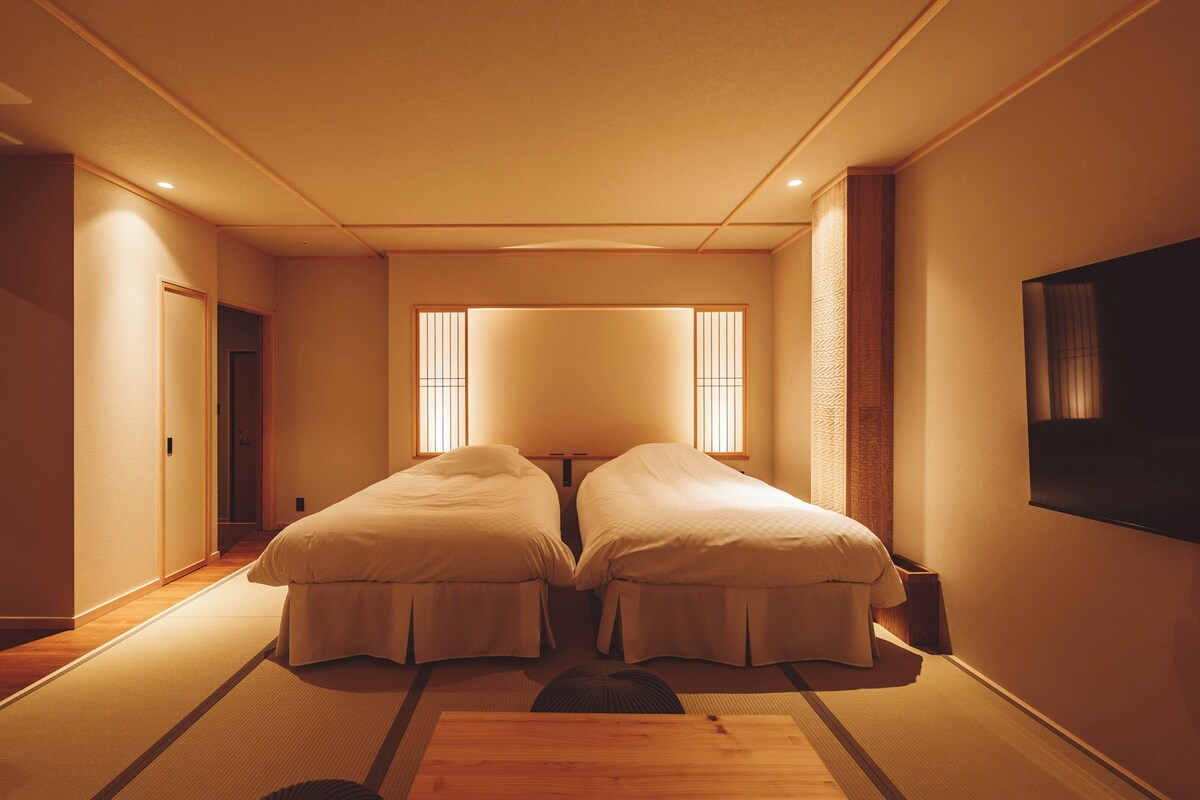 Una habitación con dos camas, televisión y puertas correderas.