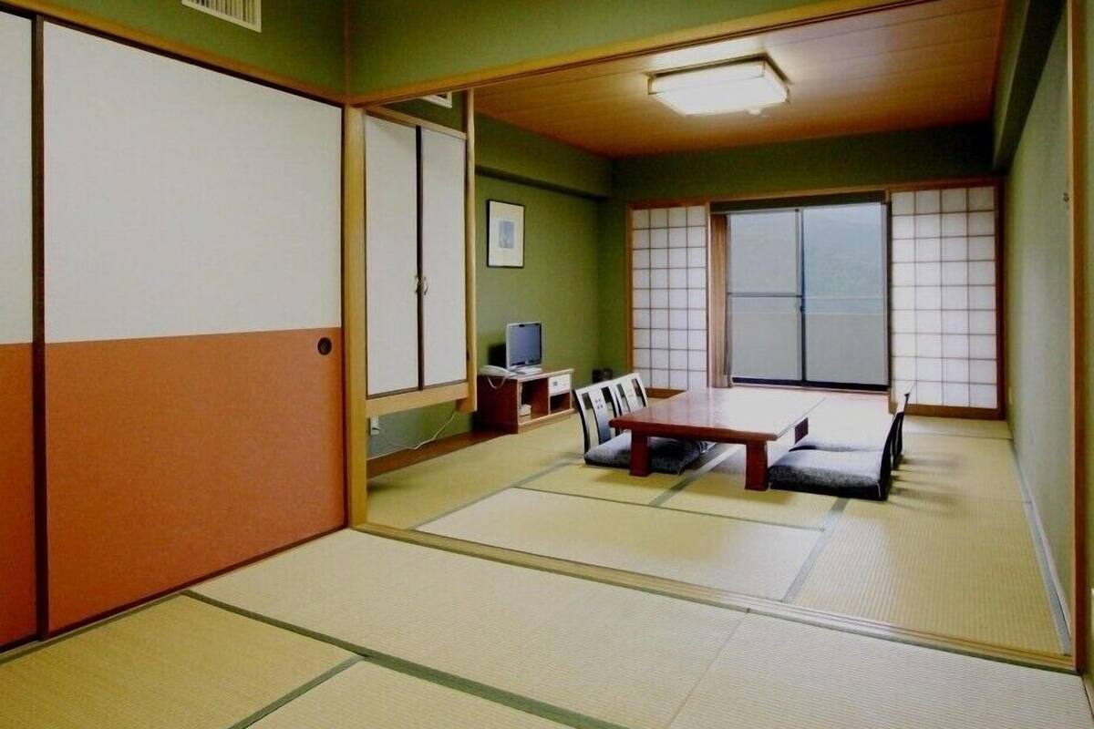 A traditional Japanese room with tatami flooring, a low table, a TV, and sliding doors.