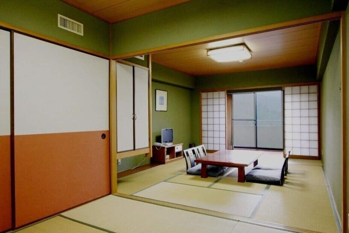 A traditional Japanese room with tatami flooring, a low table, a TV, and sliding doors.