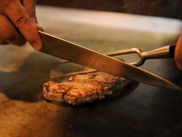 Una persona cortando carne sobre una superficie plana.