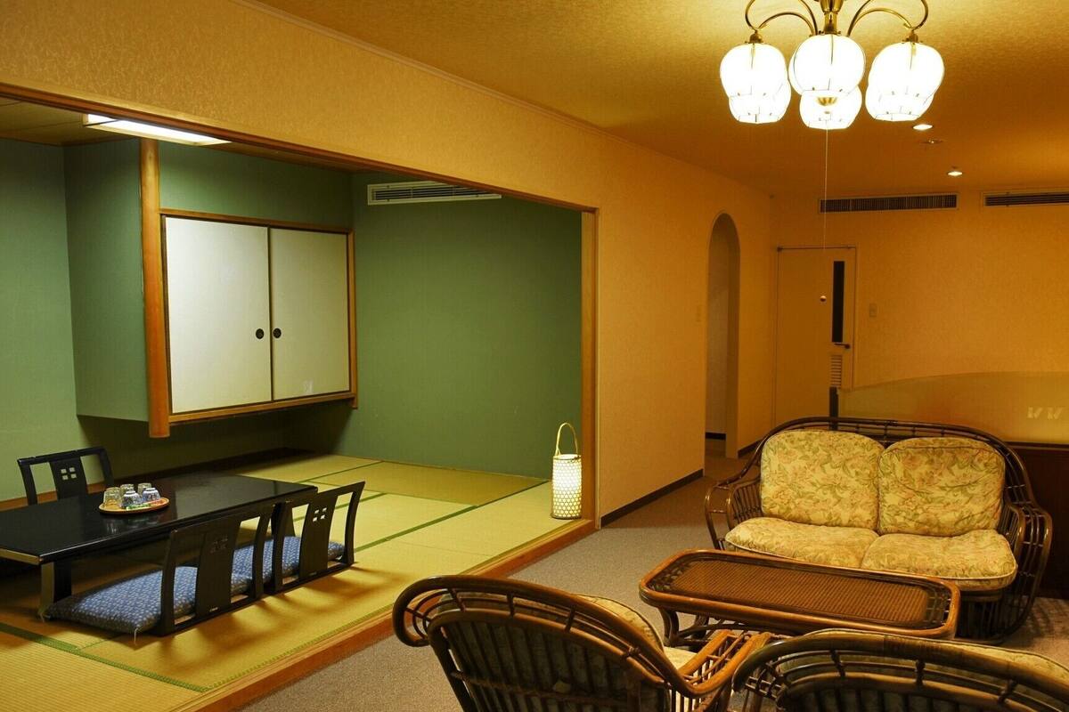 A traditional Japanese room with tatami flooring, a low table with cushions, a sofa, and a cabinet.