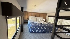 A bedroom with a bed, a window, and a bunk bed. - Modern Luxury RV Retreat and Patio, minutes from springs and beaches! (DeFuniak Springs)