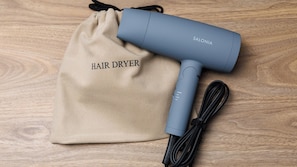 Un sèche-cheveux et un sac à cordon sur une surface en bois.