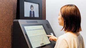 Une personne utilise un kiosque numérique doté d’un écran affichant une interface de réservation d’hôtel.