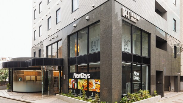 A modern hotel with a glass facade, a sign for 'NewDays,' and a visible entrance. - Hotel B4T Akabane (Tokyo)