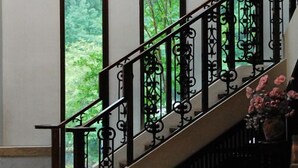 Uma escadaria com grades pretas ricamente decoradas e um patamar circular.
