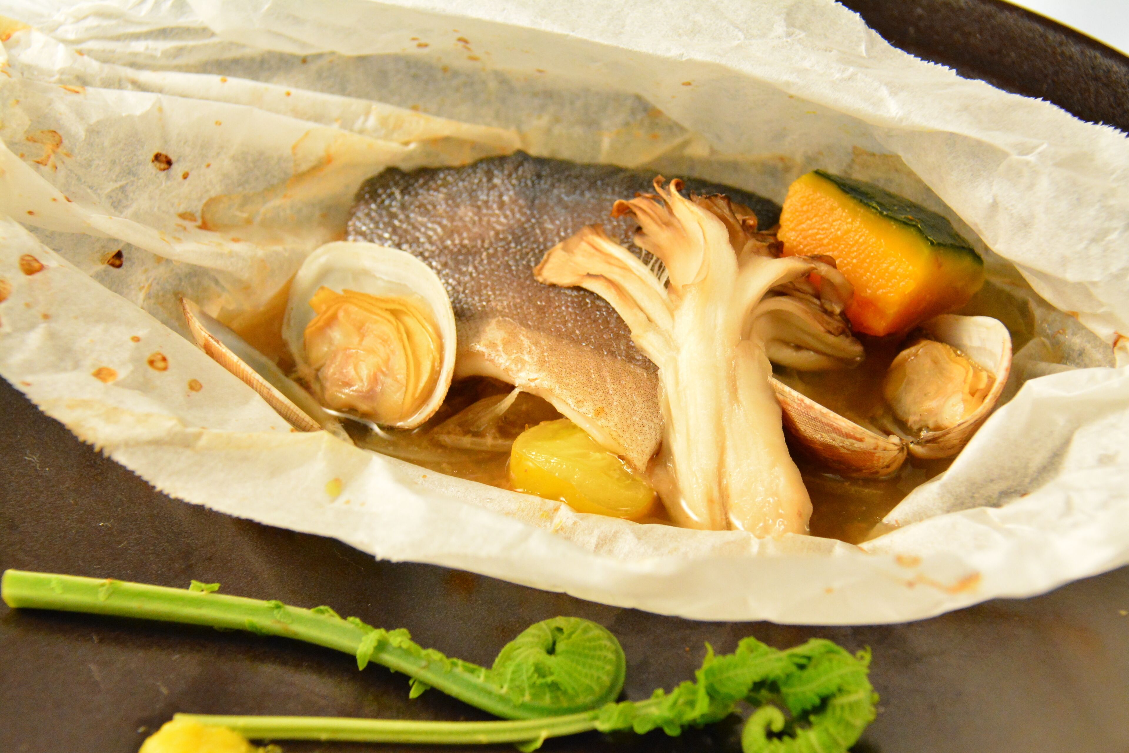 A dish with fish, vegetables, and herbs in a cooking pot.