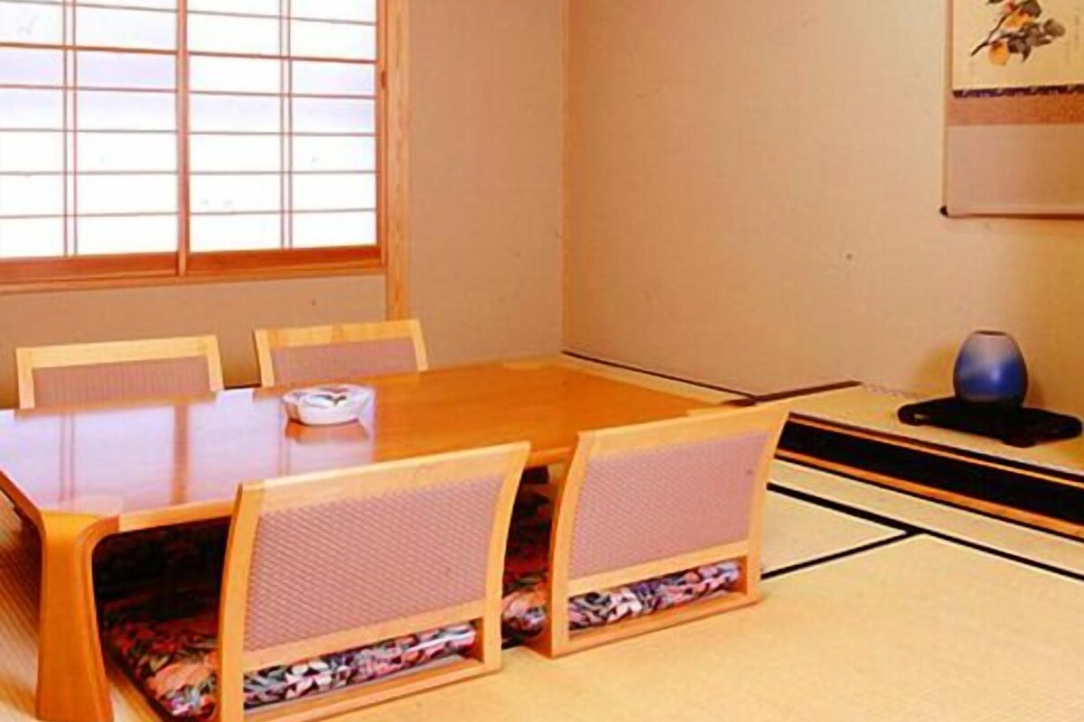 Une pièce de style japonais traditionnel, avec un sol recouvert de tatamis, une table en bois et des chaises.