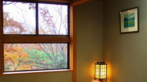 Um quarto em estilo japonês tradicional com tatames, uma mesa de madeira baixa e um painel shoji.