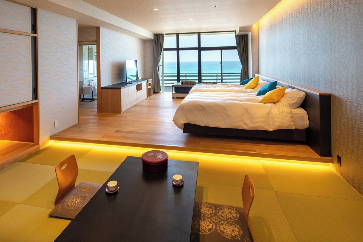 A hotel room with a bed, a desk, and a view of the ocean.