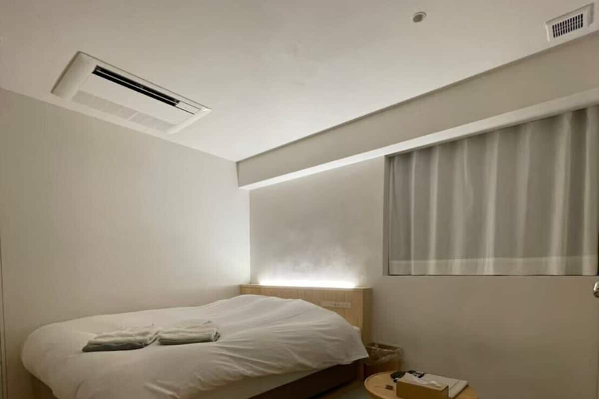 Une chambre d’hôtel moderne avec un lit simple, une petite table ronde et une fenêtre avec des rideaux.