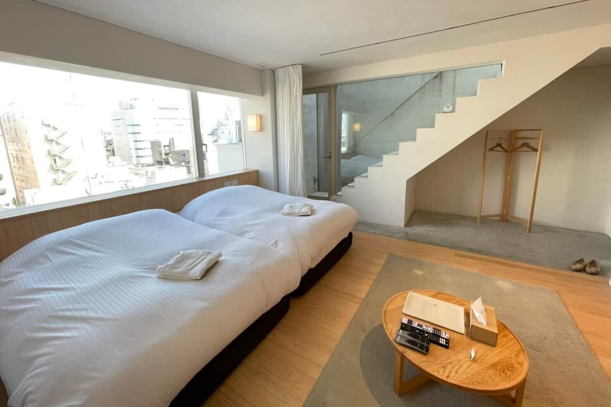 Une chambre d’hôtel moderne avec deux lits, un escalier et une vue sur la ville.