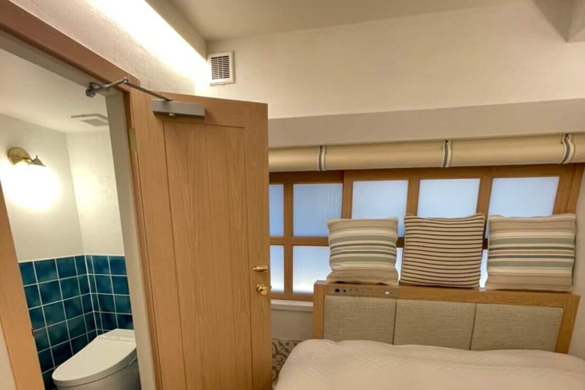 Une chambre d’hôtel avec un lit, une salle de bain et une fenêtre équipée de stores.