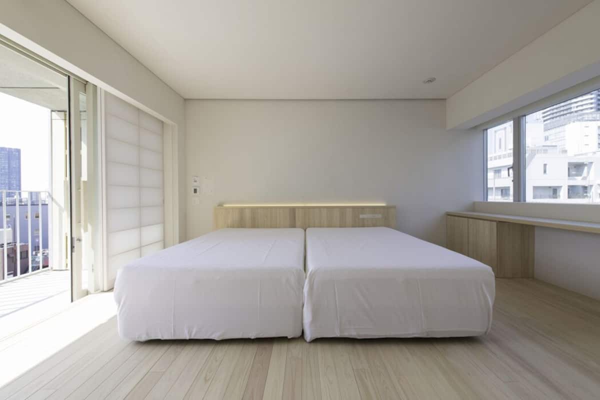 Une chambre moderne dotée d’une grande fenêtre, d’un balcon et d’une tête de lit en bois.