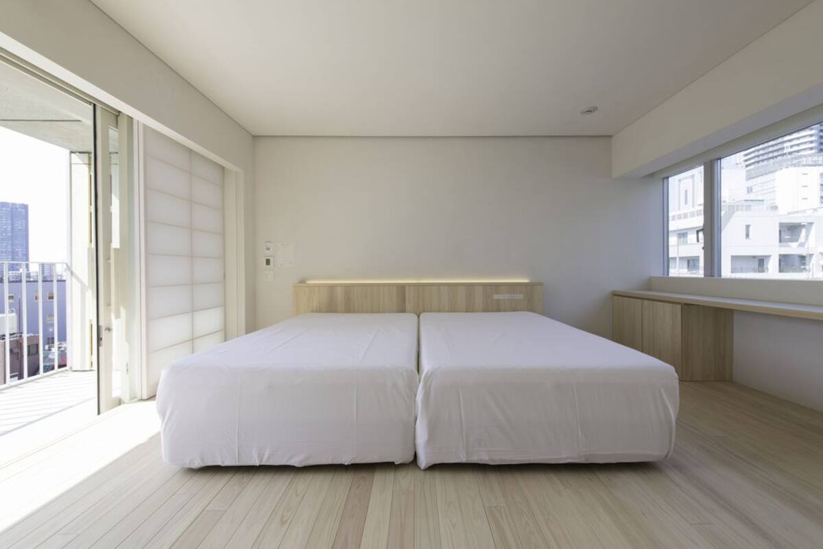 A modern bedroom with a large window, a balcony, and a wooden headboard.