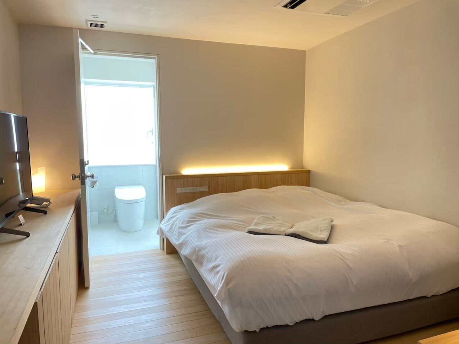 A bedroom with a bed, bedside table, and a door leading to a bathroom.
