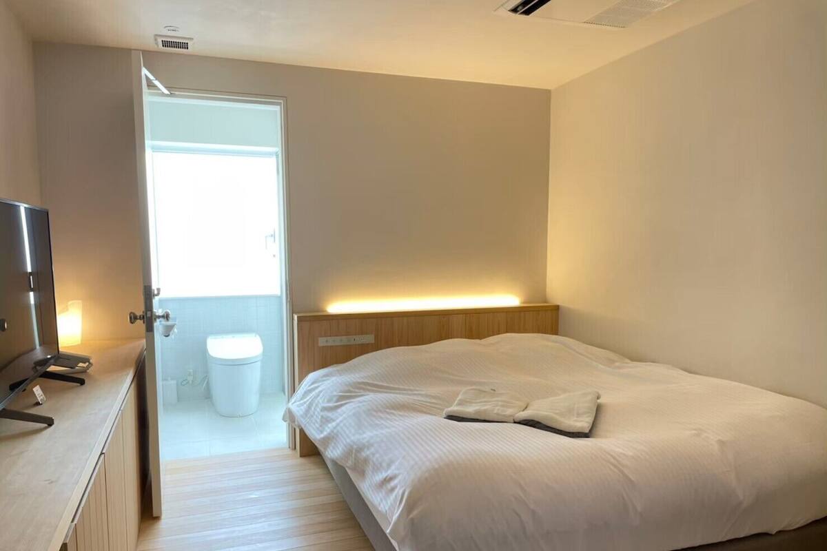 A bedroom with a bed, bedside table, and a door leading to a bathroom.