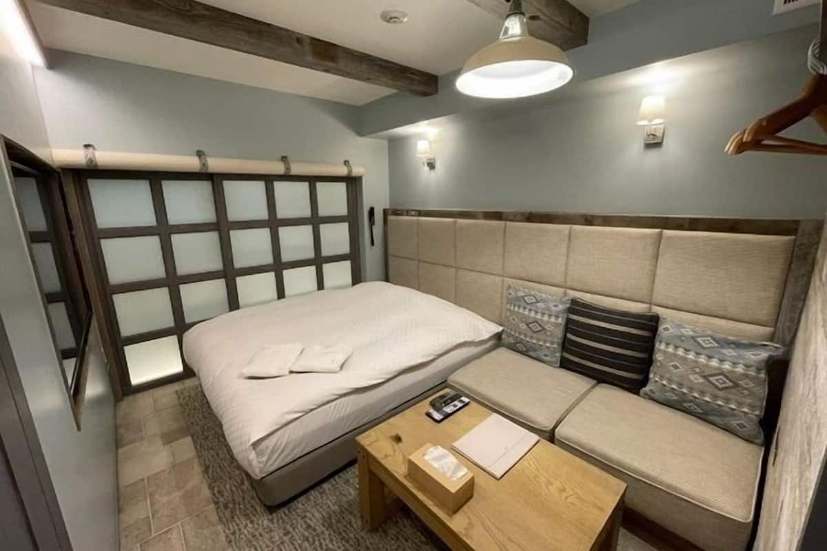 Une chambre à coucher comprenant un lit, un canapé, une table basse en bois et un luminaire suspendu.