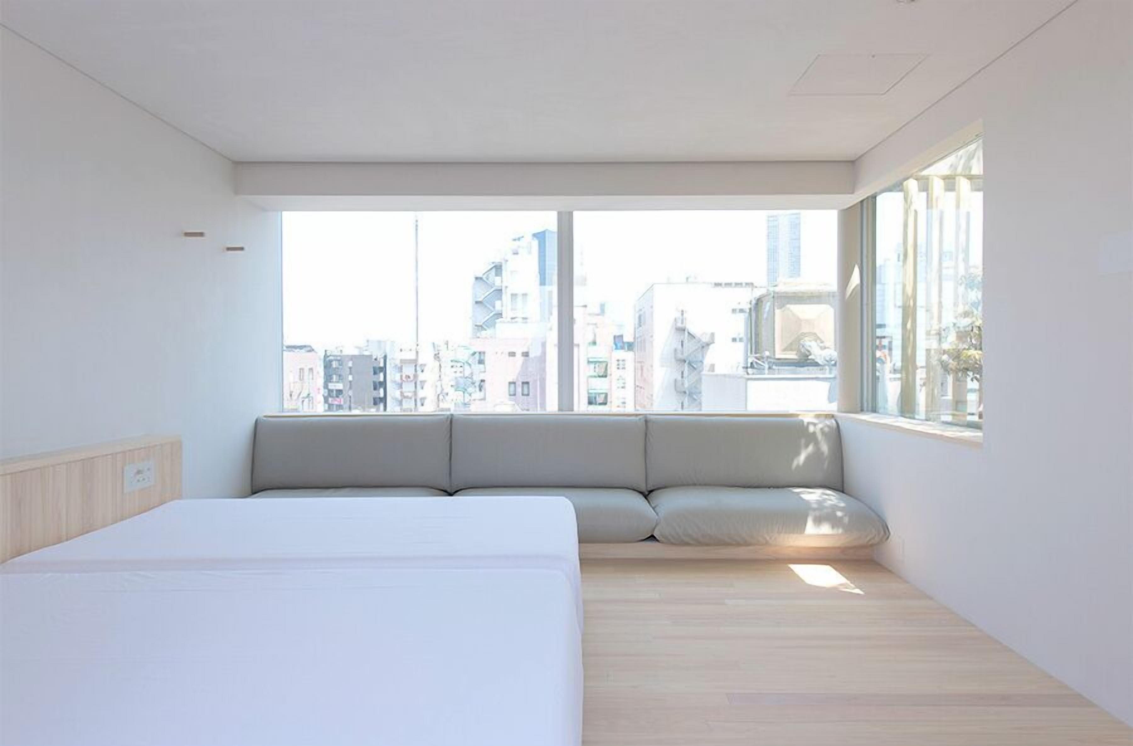 A modern hotel room with a large bed, a window seat, and a city view.