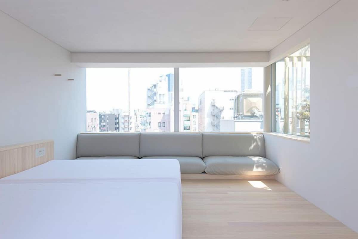 Une chambre d’hôtel moderne avec un grand lit, un coin fenêtre aménagé et une vue sur la ville.