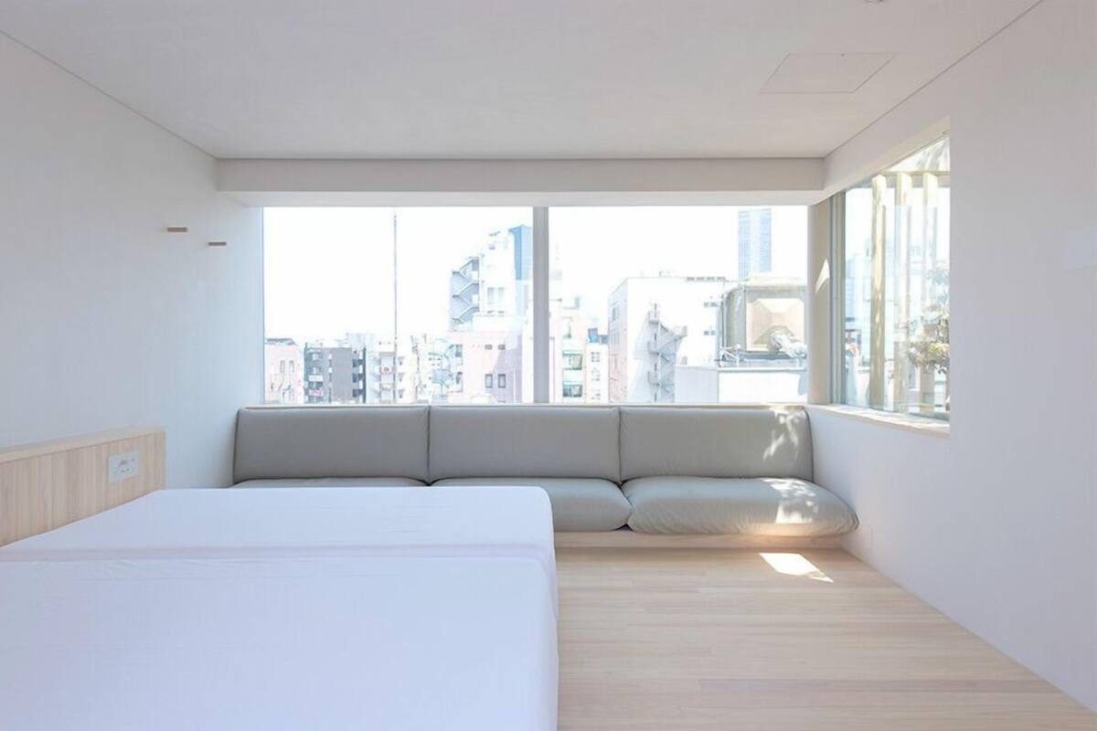 A modern hotel room with a large bed, a window seat, and a city view.