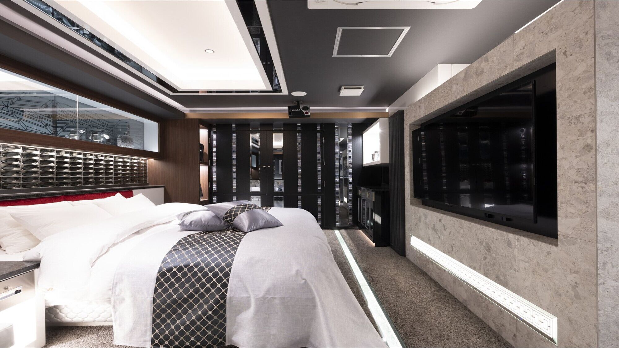 A modern bedroom with a large bed, built-in wardrobe, and a large window.