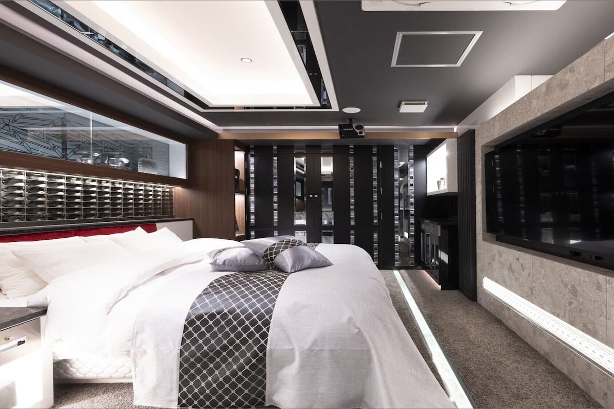 Une chambre moderne avec un grand lit, une armoire intégrée et une grande fenêtre.