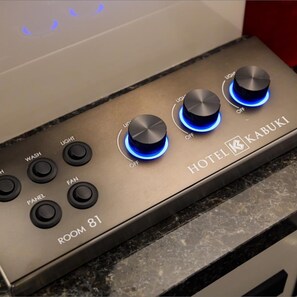 A control panel with multiple buttons labeled 'WASH,' 'LIGHT,' 'FAN,' and 'PANELS,' and a brand name 'KABUKI' on a metallic surface. - Hotel Kabuki (Tokyo)