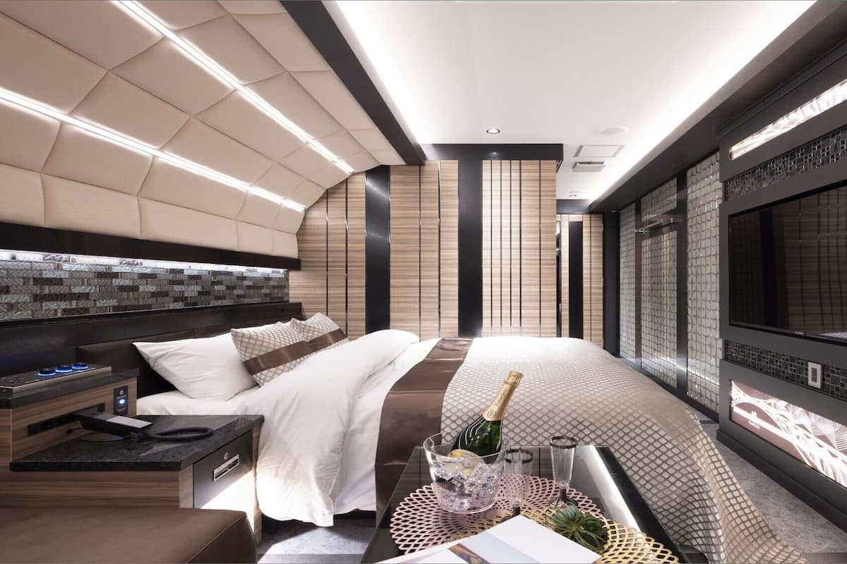 Une chambre d’hôtel moderne équipée d’un lit, d’une table de chevet, d’un minibar et d’un grand écran de télévision.