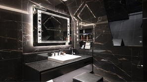 A modern bathroom with a large mirror, a white sink, and marble walls. - Hotel Kabuki (Tokyo)