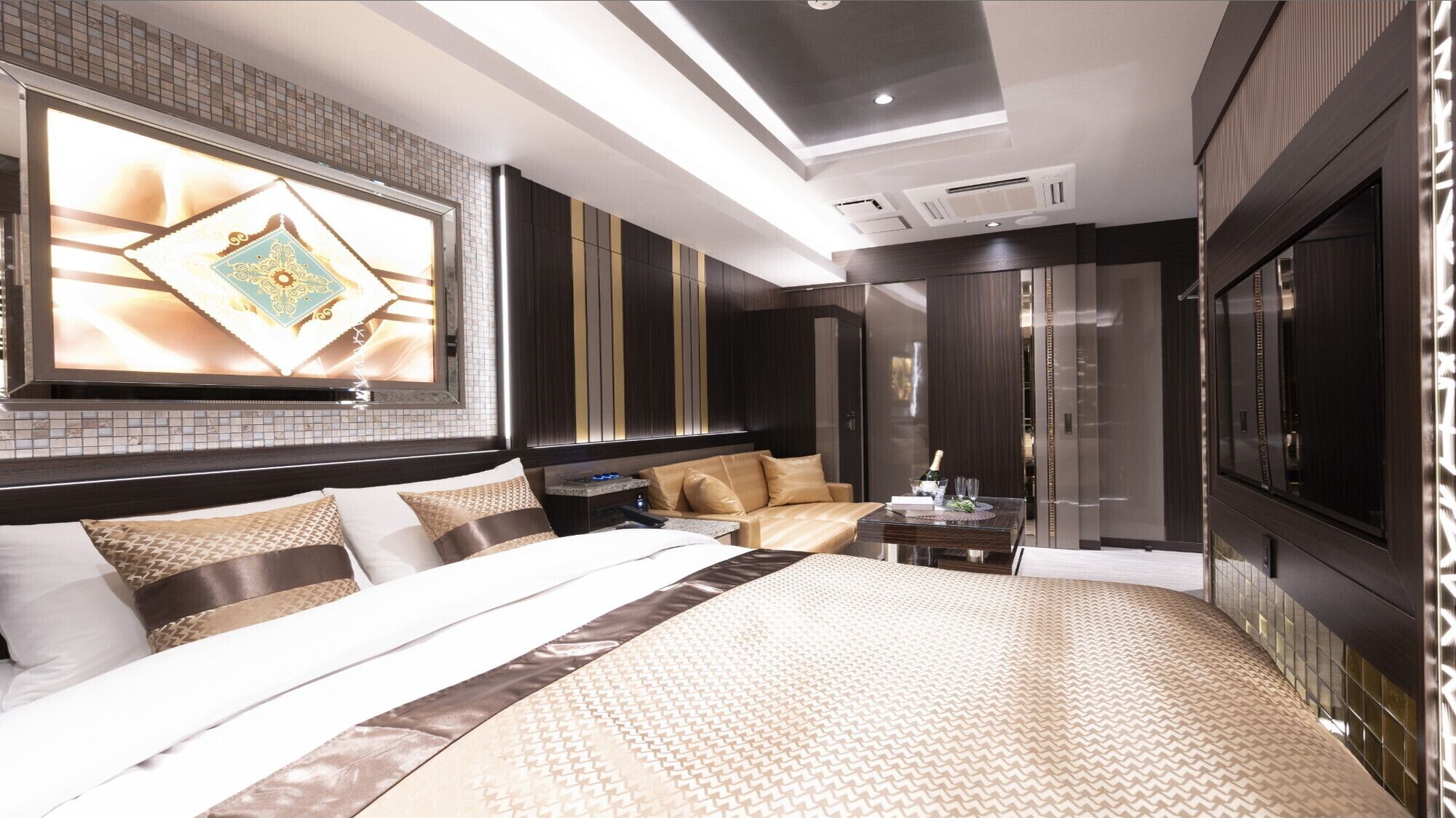 A modern hotel room with a large bed, a seating area, a TV, and a minibar.