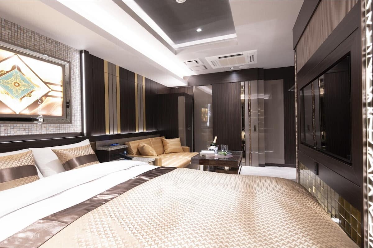 Une chambre d’hôtel moderne dotée d’un grand lit, d’un coin salon, d’une télévision et d’un mini-bar.