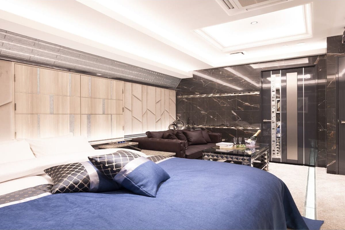 Une chambre moderne comprenant un lit, un canapé, une table basse en verre et un mini-bar.