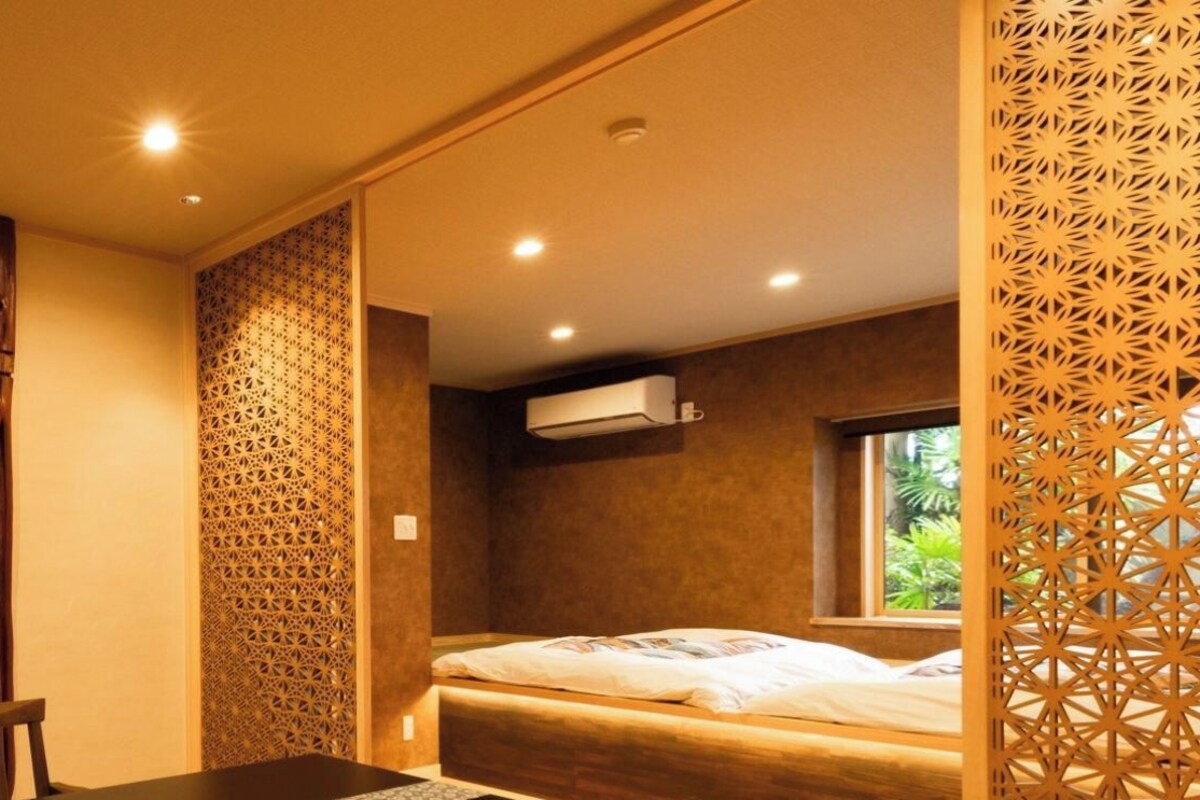 Quarto com cama, janela e ar-condicionado fixado na parede.