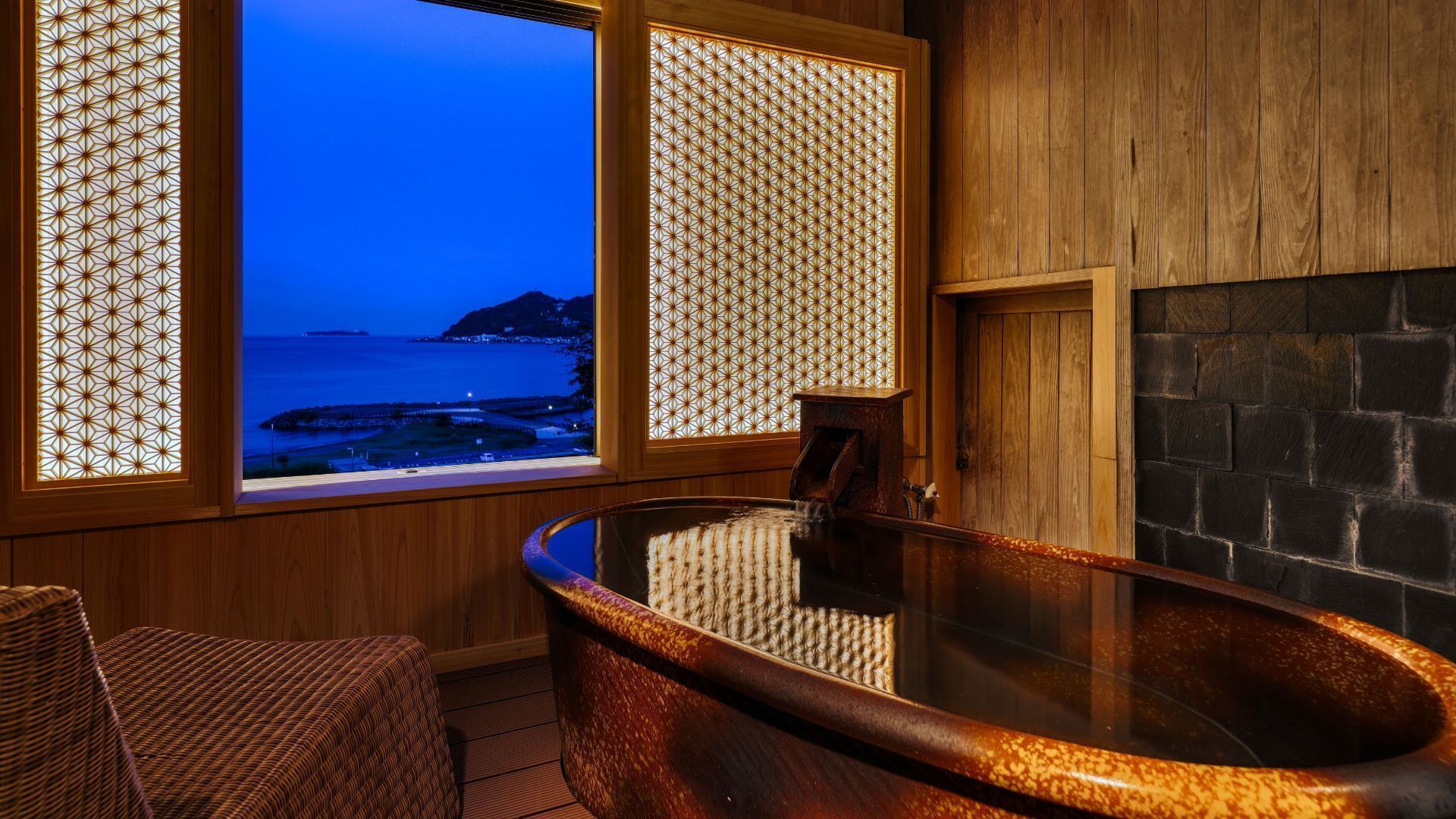 Ein Wellnessraum mit Whirlpool, Holzwänden und Blick auf den Ozean.