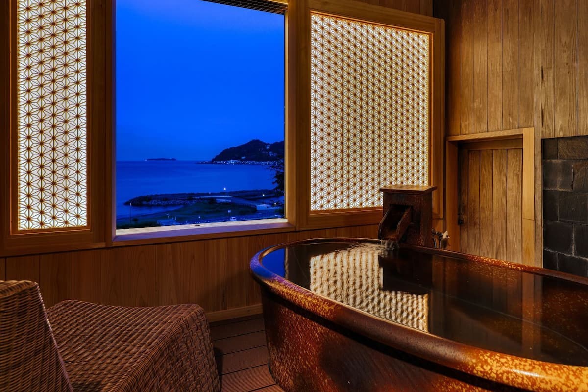 Ein Wellnessraum mit Whirlpool, Holzwänden und Blick auf den Ozean.