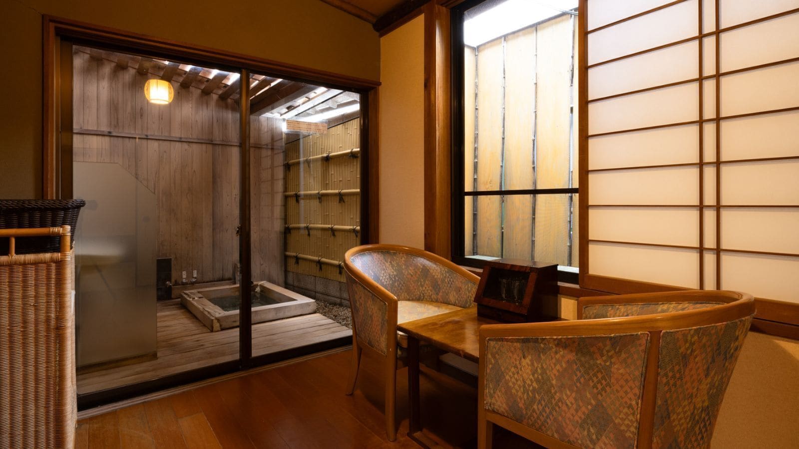 Ein traditioneller japanischer Raum mit Tatami-Bodenbelag, einer Schiebetür zu einem Waschbecken und Blick durch einen Shoji-Bildschirm.