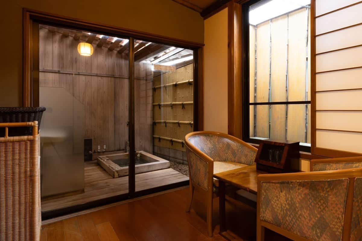 Ein traditioneller japanischer Raum mit Tatami-Bodenbelag, einer Schiebetür zu einem Waschbecken und Blick durch einen Shoji-Bildschirm.