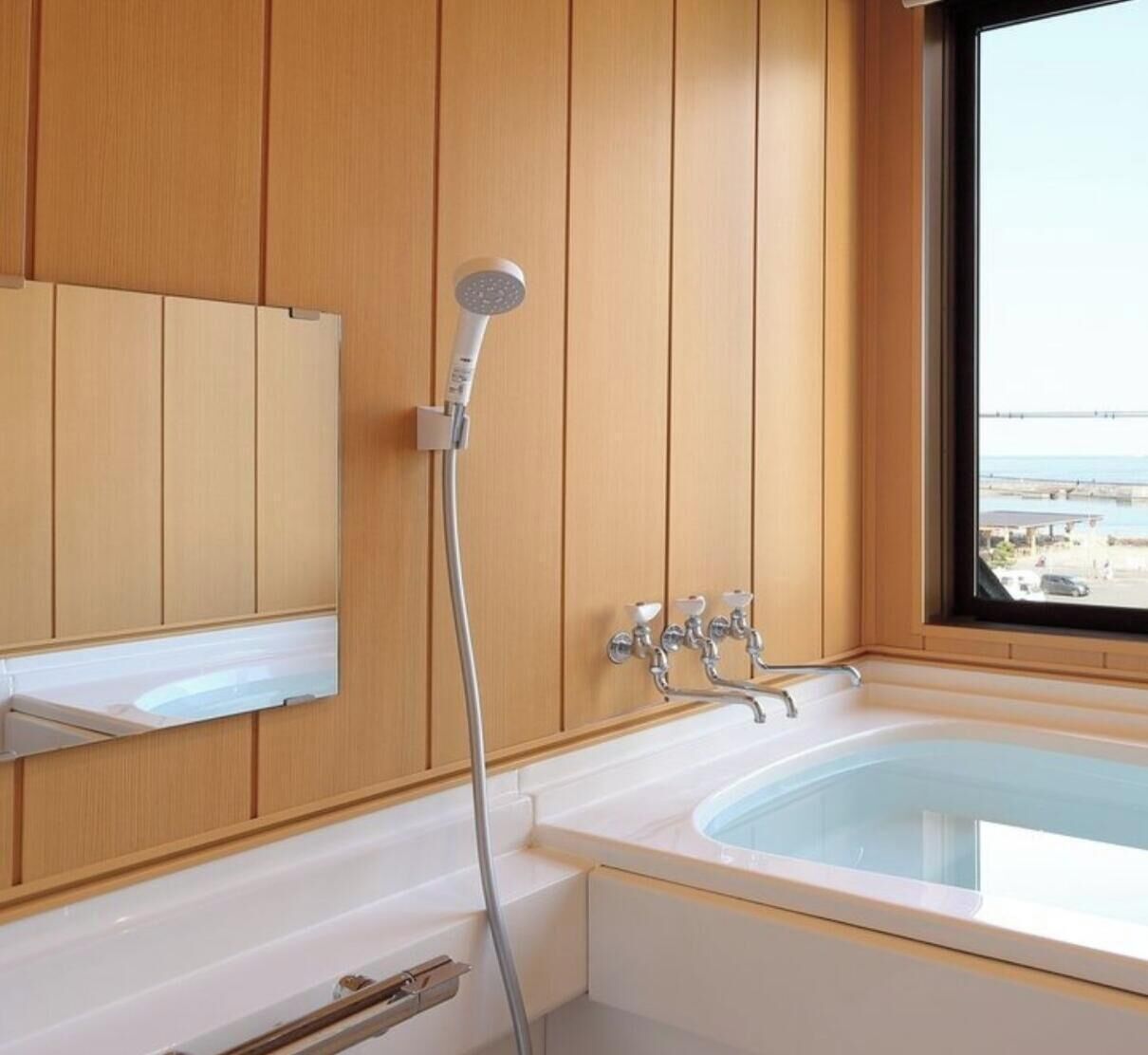 Ein Badezimmer mit Badewanne, Dusche, einem Fenster mit Blick und Holzvertäfelung.