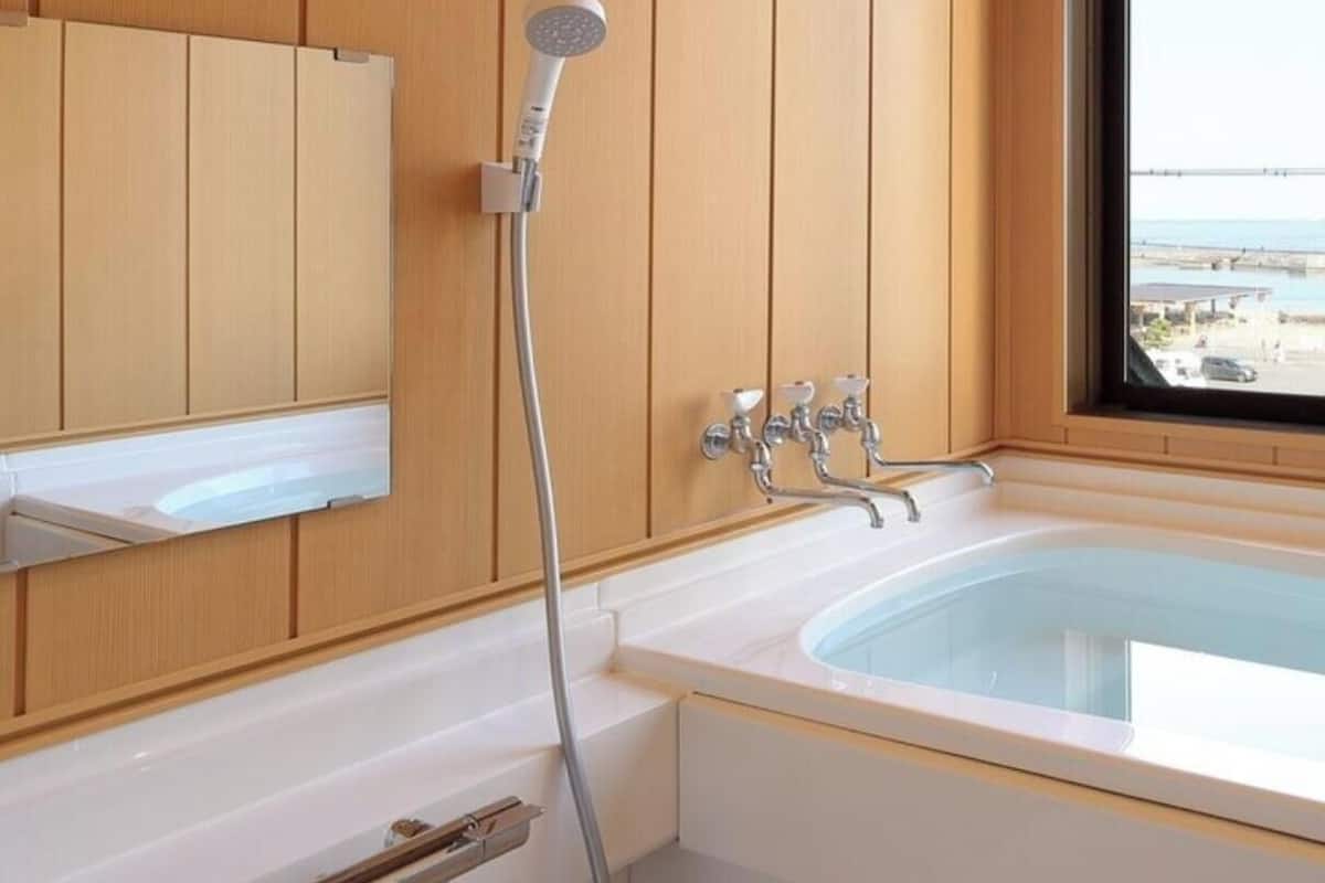 Ein Badezimmer mit Badewanne, Dusche, einem Fenster mit Blick und Holzvertäfelung.