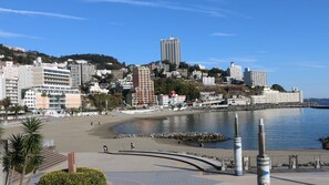 A coastal cityscape with a beach, buildings, and a clear sky. - Atami Onsen Umibe no Yado Nagahamaen (Atami)