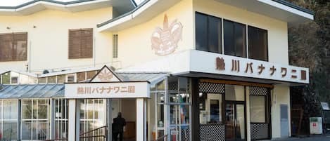 A building with a sign reading 'Atagawa Tropical & Alligator Garden' and another sign for 'Hot River Banana Garden'.