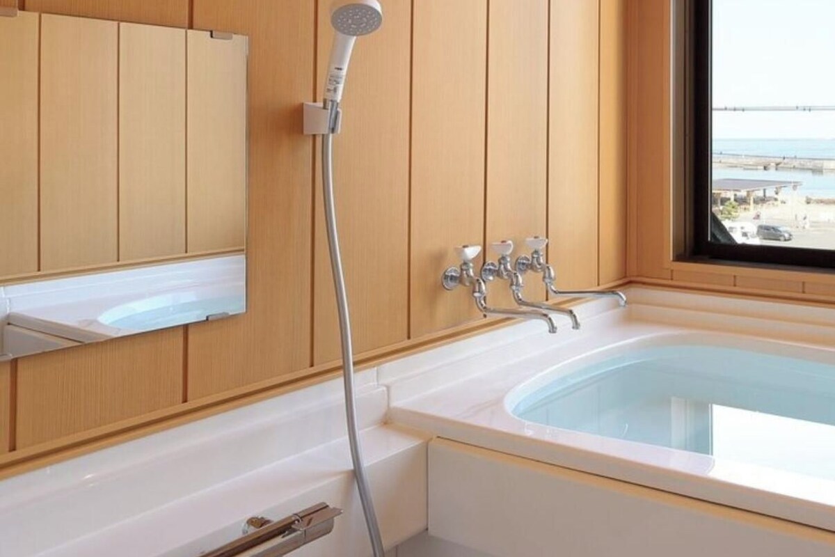 Un baño con bañera, ducha y ventana con vistas.