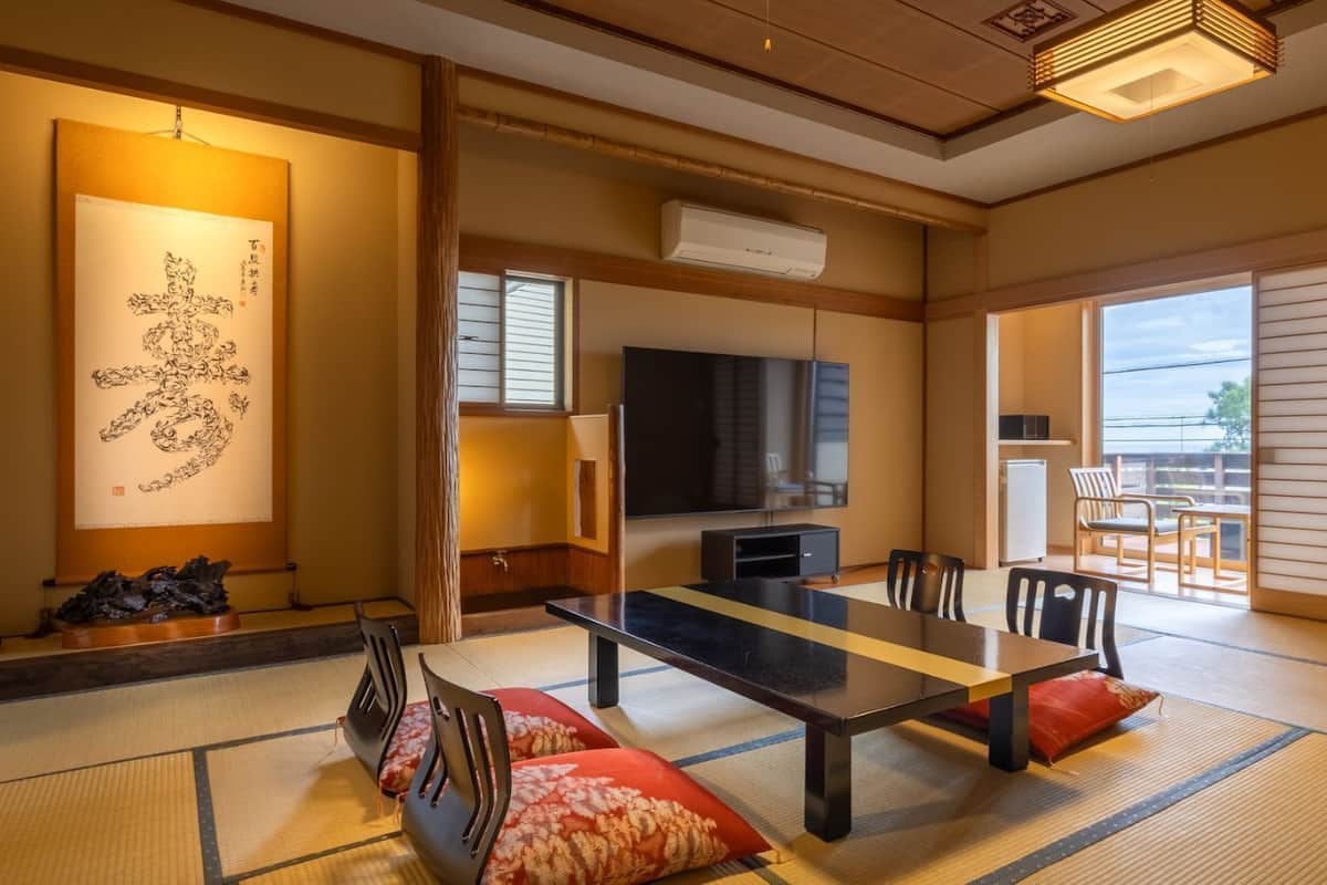 Ein traditioneller japanischer Raum mit Tatami-Bodenbelag, einem niedrigen Tisch und einer Schiebetür zu einem Balkon.