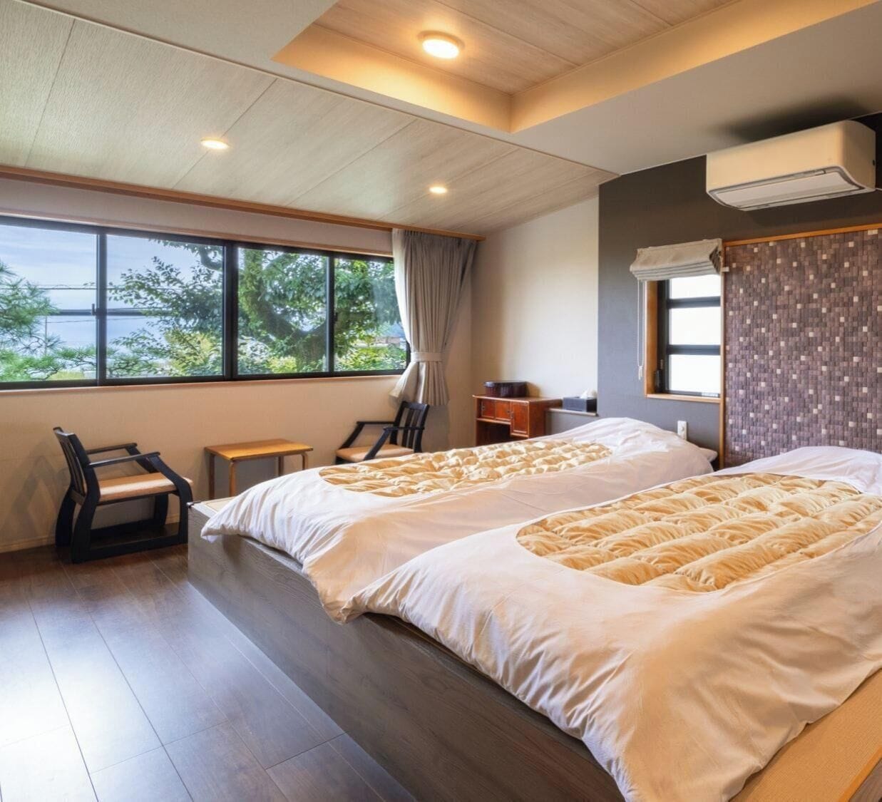 Ein Hotelzimmer mit zwei Betten, einem Fenster mit Blick, einem Schreibtisch und einem Stuhl.