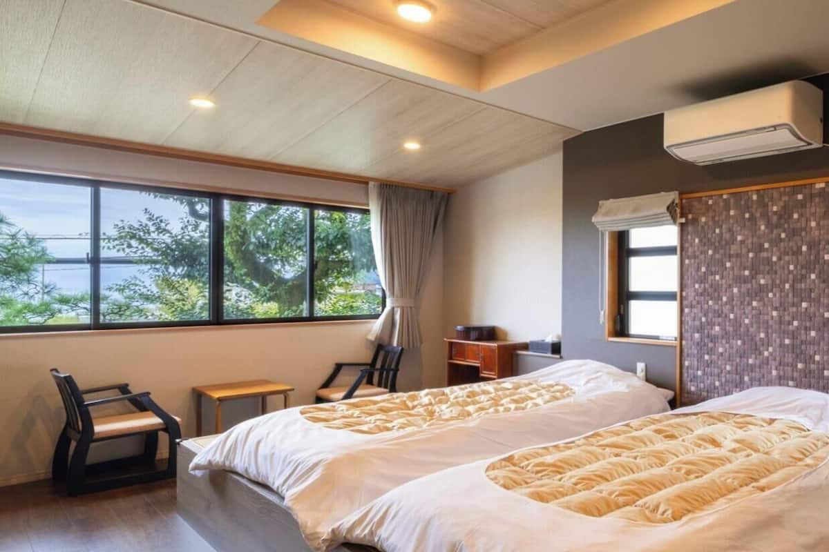 Ein Hotelzimmer mit zwei Betten, einem Fenster mit Blick, einem Schreibtisch und einem Stuhl.