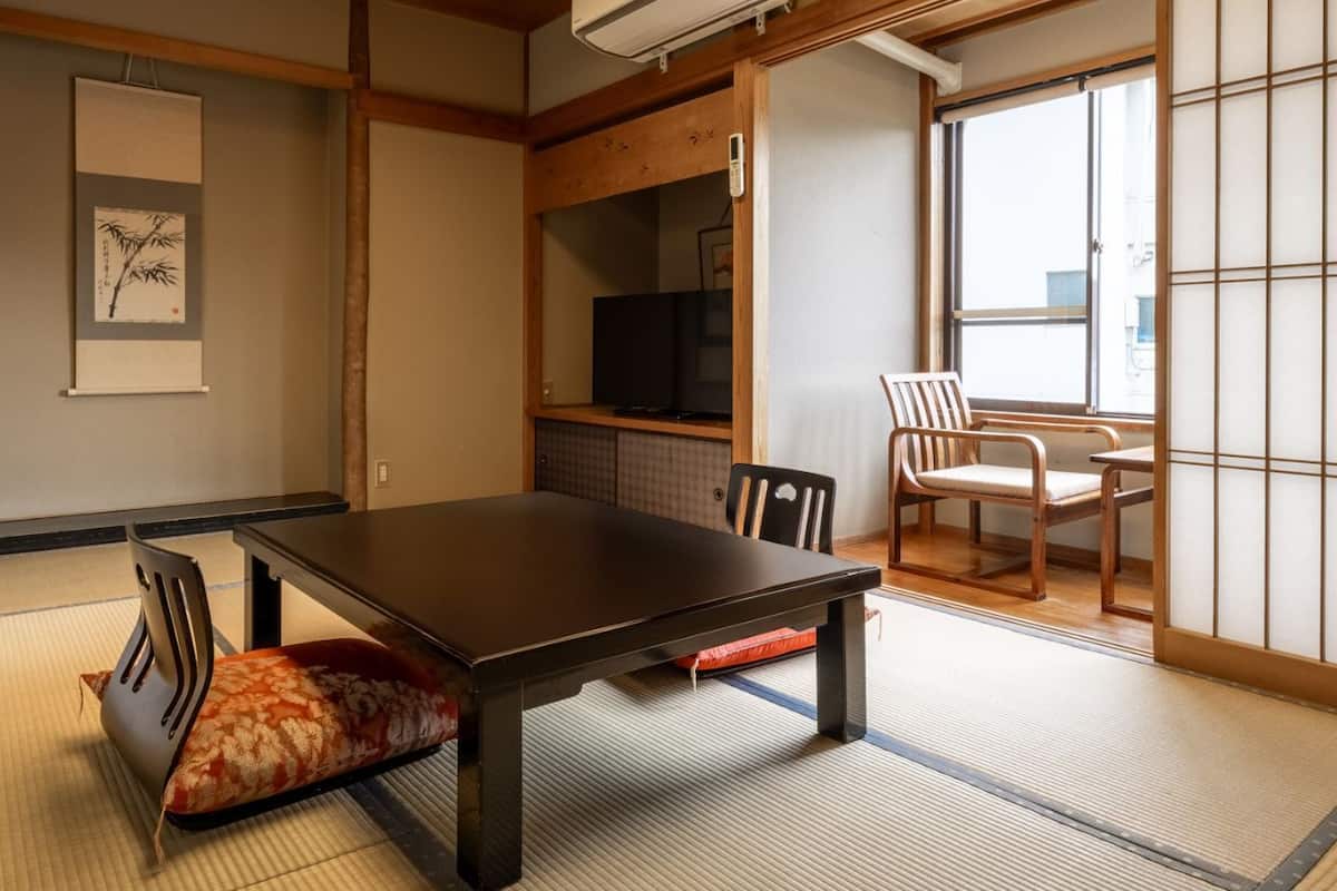 Ein traditioneller japanischer Raum mit Tatami-Boden, einem niedrigen Tisch und Schiebetüren.