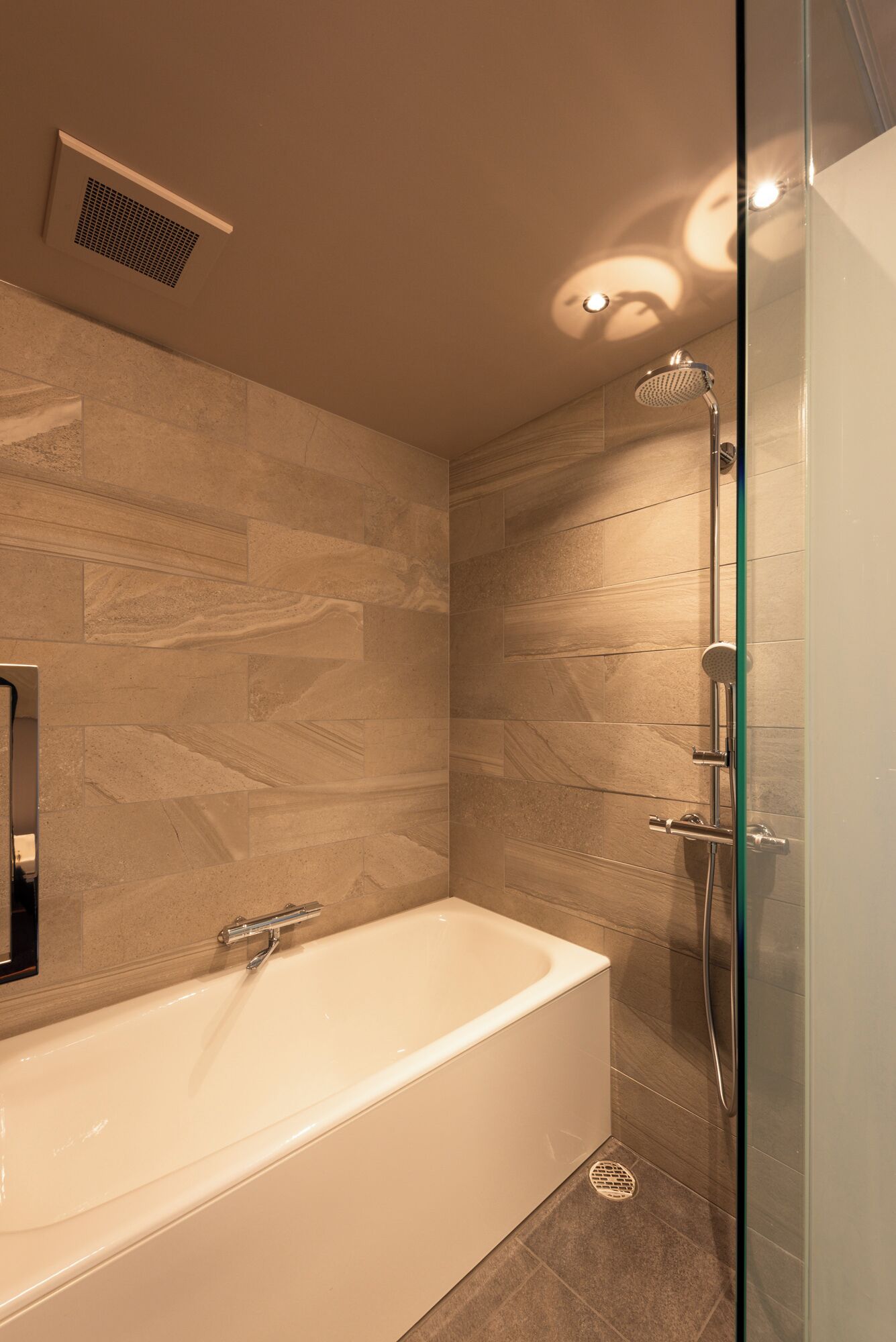 Une salle de bain moderne avec une baignoire sur pieds, une cabine de douche en verre et un système de ventilation fixé au mur.